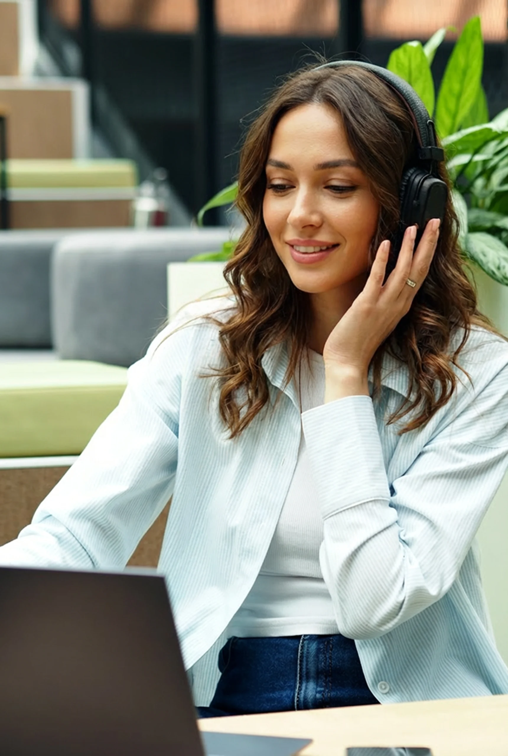 A woman wearing a headset sits at a desk, focused on her work